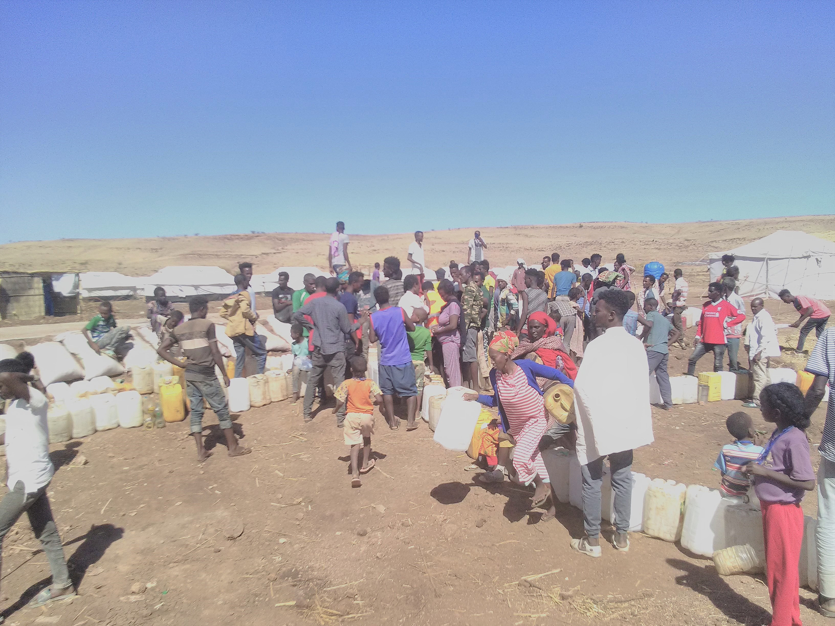 People queuing for water in Um Rakuba refugee camp after there was no supply for two days