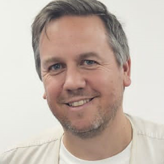 Photo of a man with grey hair wearing a white T shirt