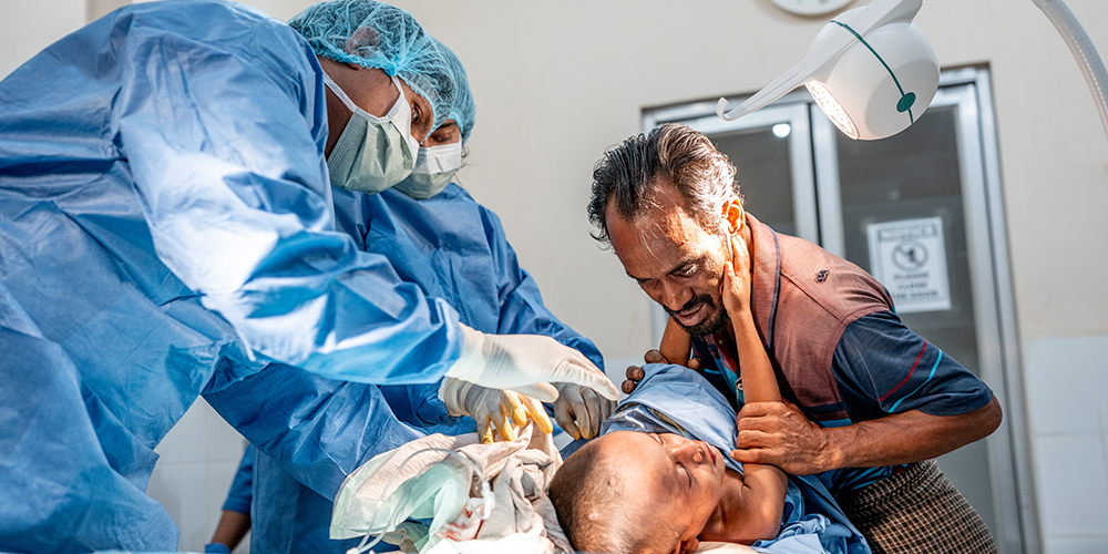 Four-year-old Shofi is comforted by his father while receiving treatment for multiple abscesses in the emergency room of the MSF Kutupalong Hospital, Bangladesh